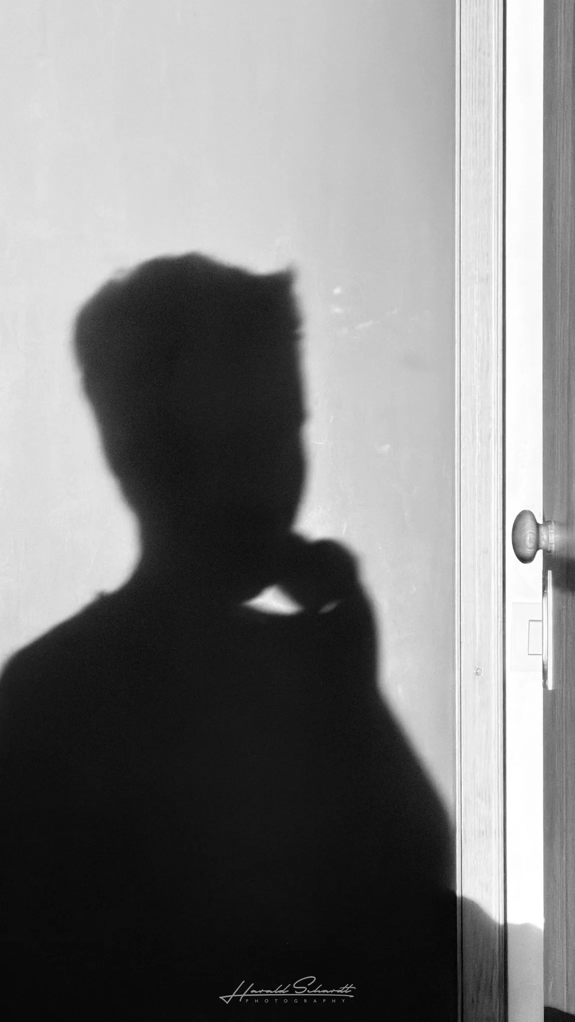 Shadow silhouette of a child holding a burrito, projected onto a wall in bright midday light.