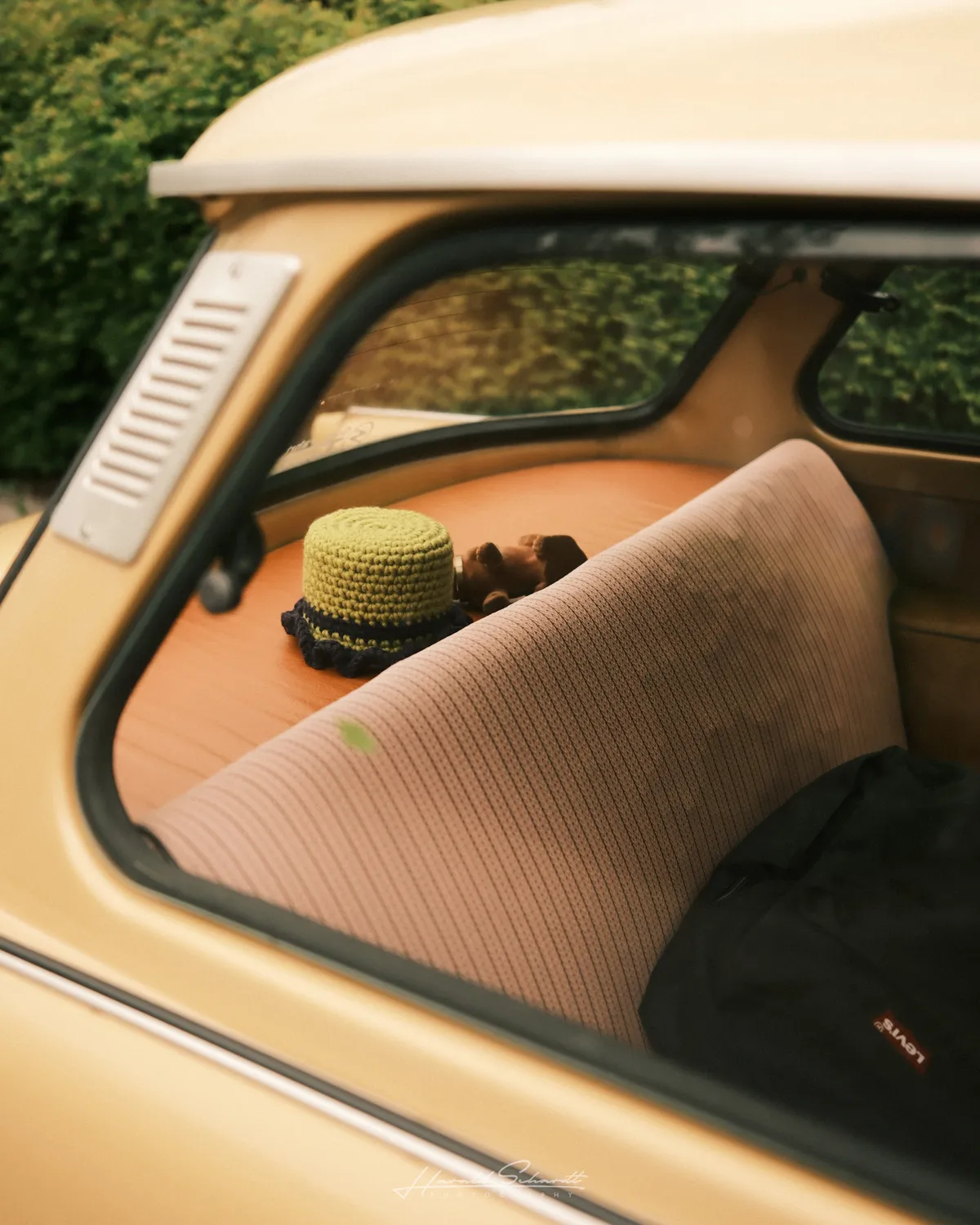 View through the rear window of a Trabant. Back seat and parcel shelf visible, small crocheted hat resting on the shelf.