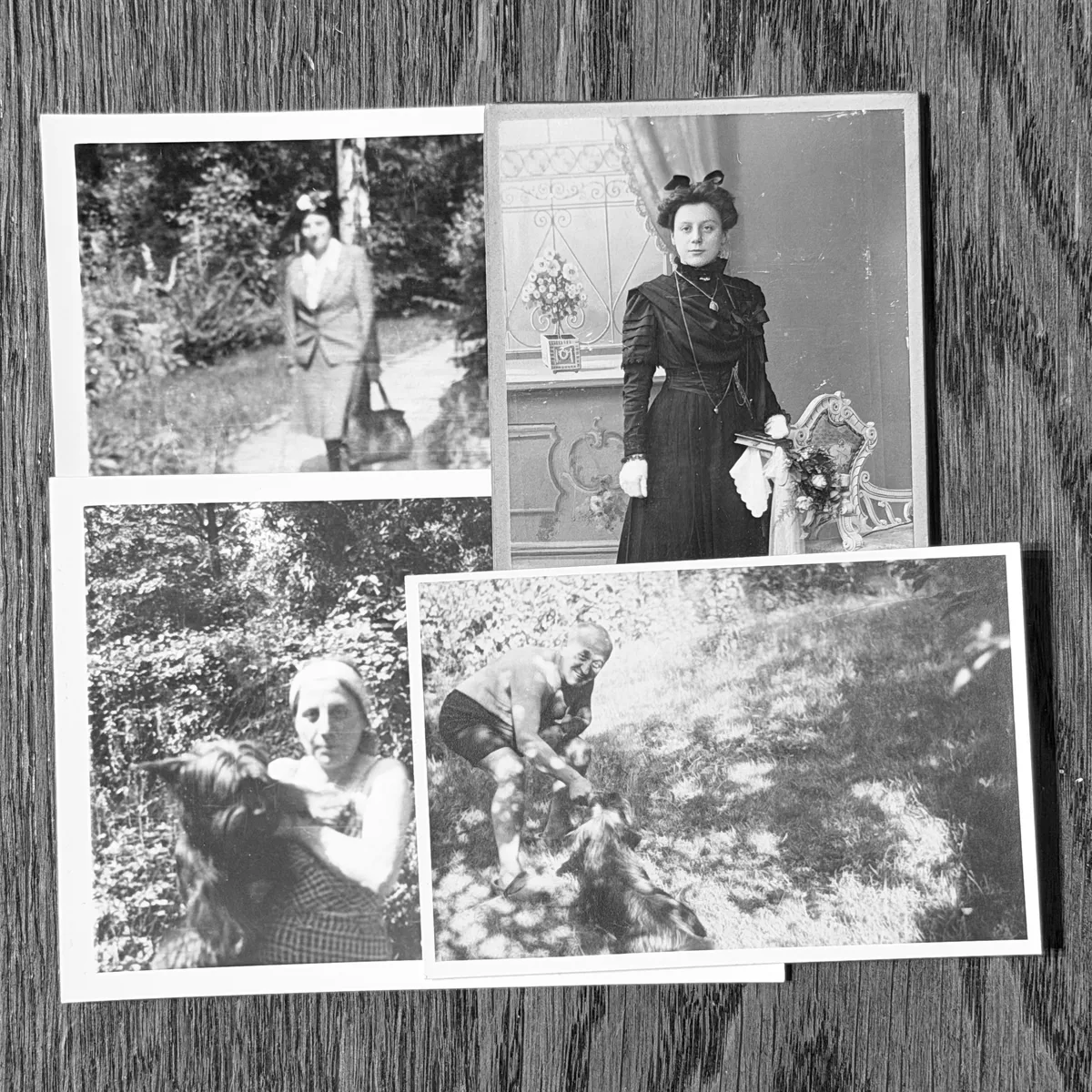 A scattered pile of old black-and-white family photos on a wooden table.