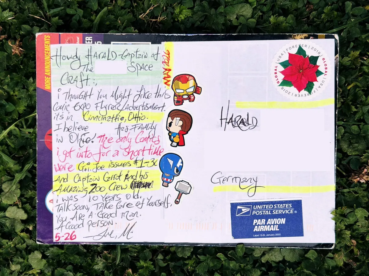 Back of a handwritten postcard addressed to Harald in Germany, decorated with Iron Man, Thor, and Captain America stickers, a Forever stamp, and a personal note in blue and red ink.