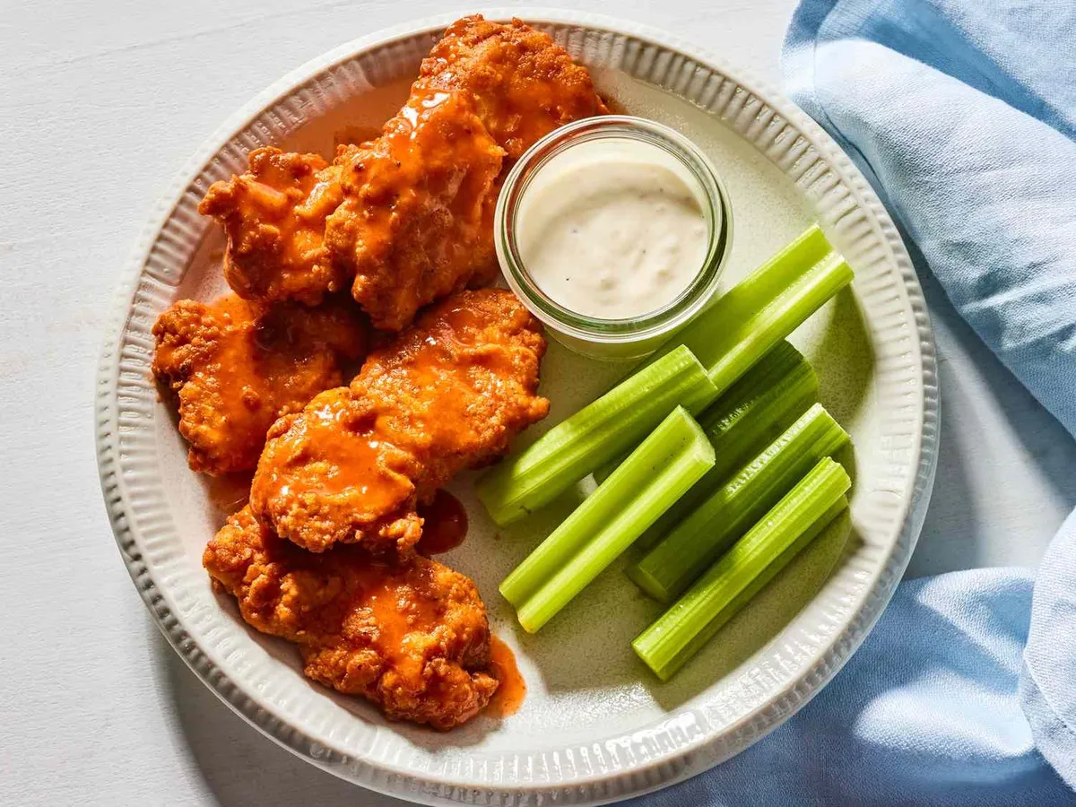 A plate of boneless wings, celery and salad dressing