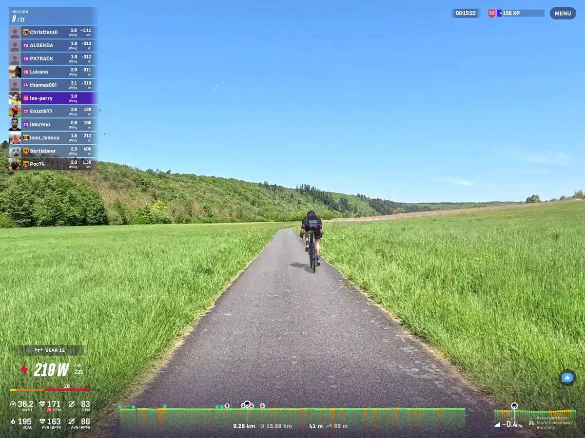 Riders' avatar cycling through green fields below a blue sky on Rouvy