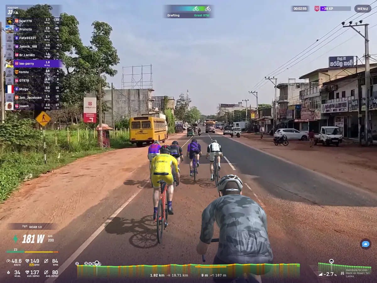 Screenshot from Rouvy showing cyclists avatars riding through a Sri Lankan village