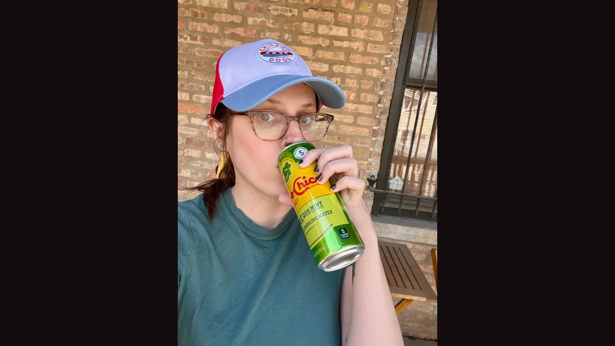 Megan drinking a Topo Chico and wearing a Chicago Dogs hat