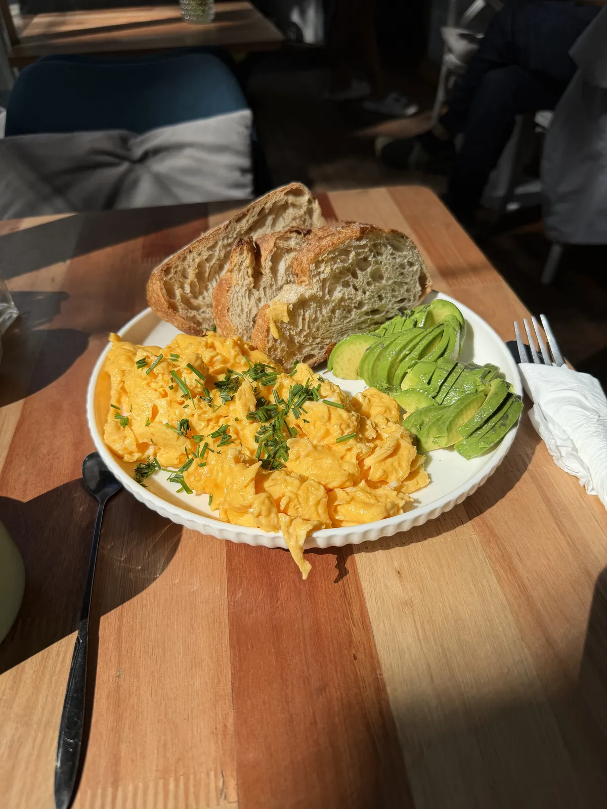 scrambled eggs with avocado and bread on the side