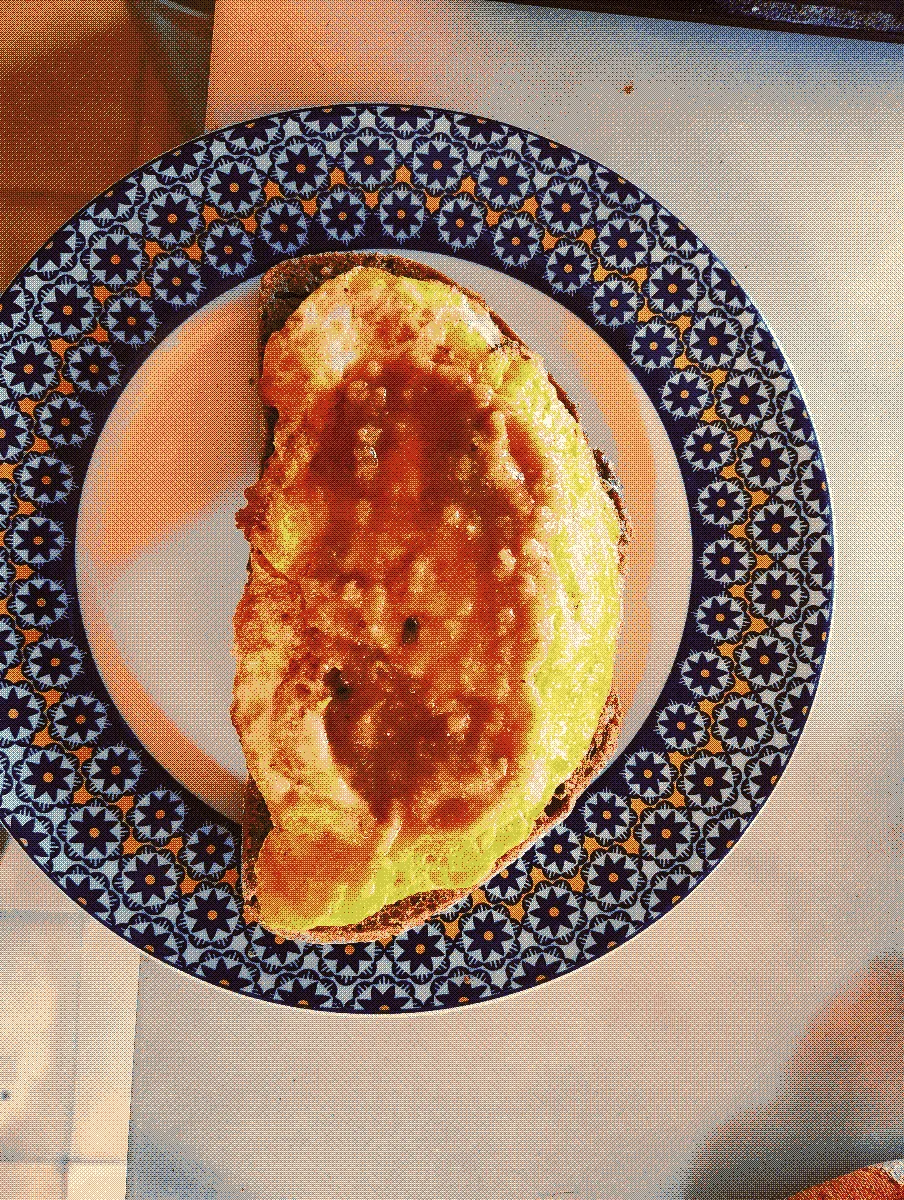 A slice of bread with scrambled egg on top. The shape of the egg is almost identical to bread