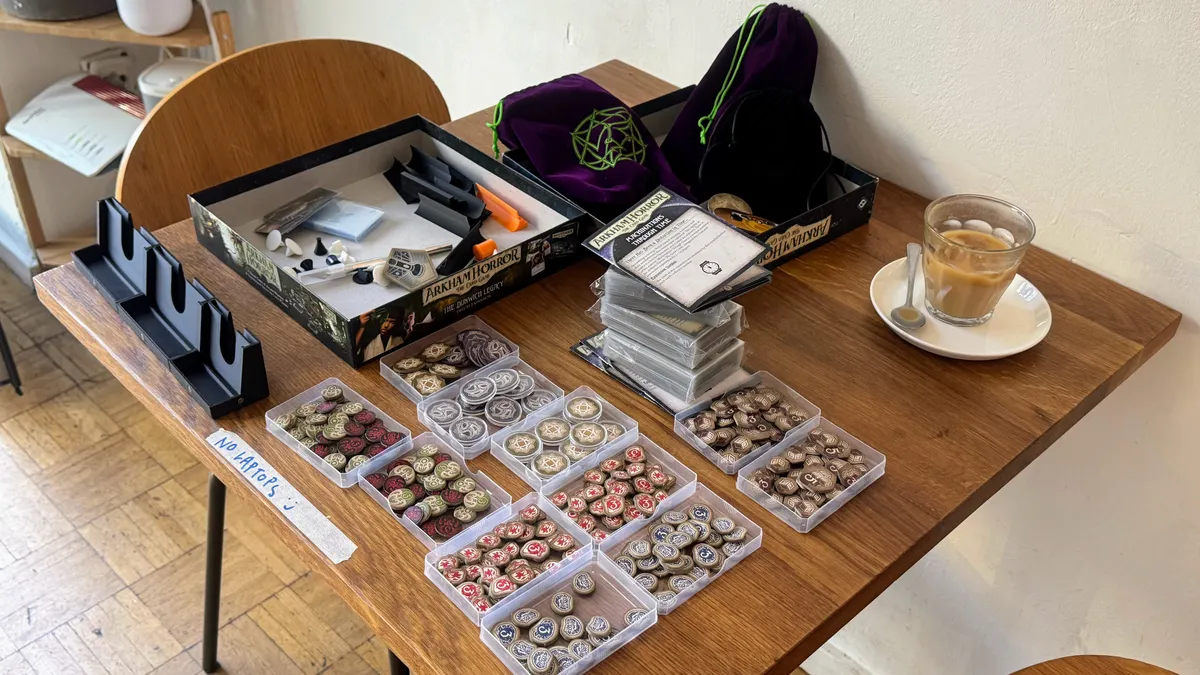 A coffee shop table covered in board game tokens and cards.