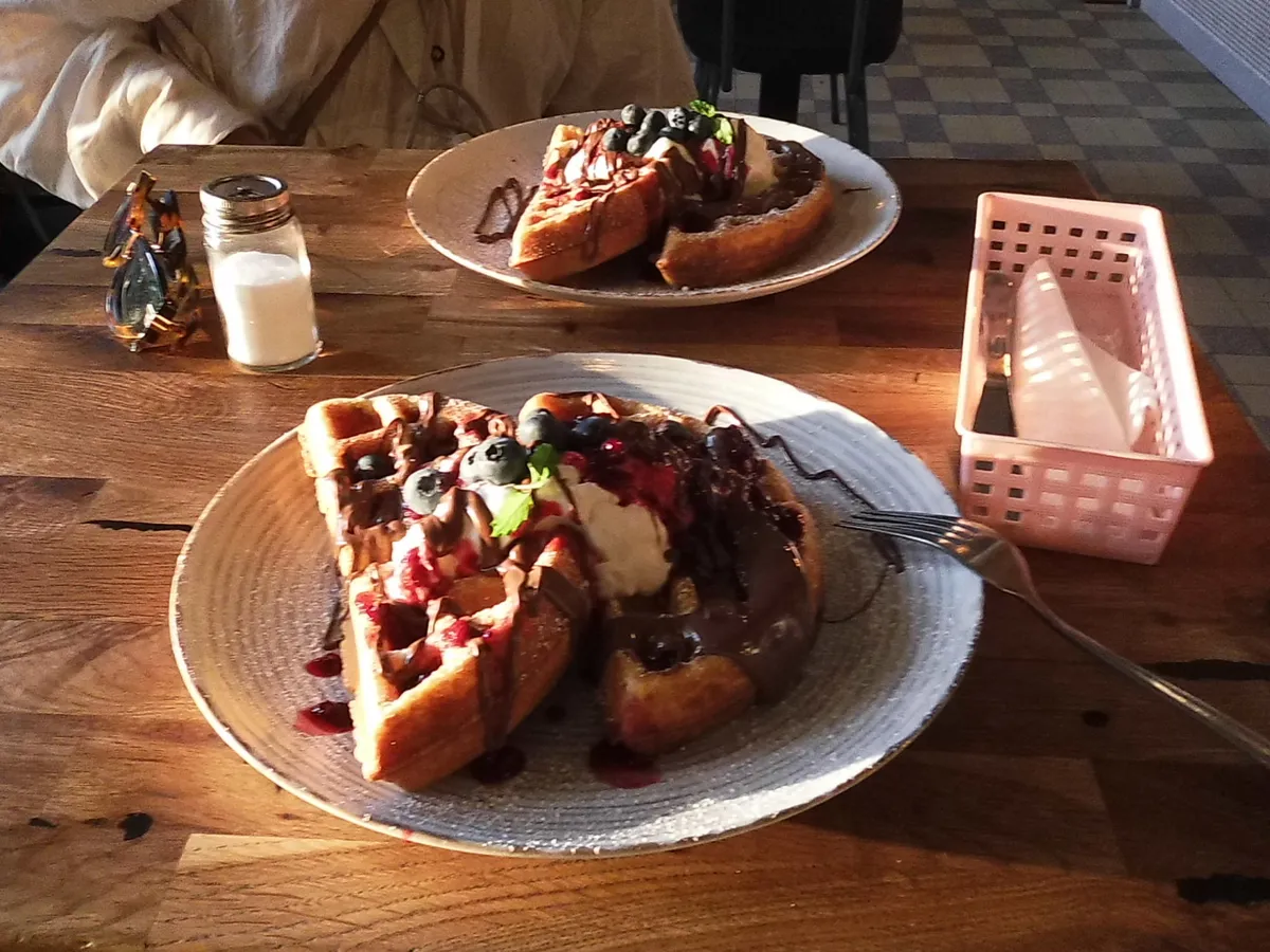 restaurant table, two plates with waffles with sweet stuff on top