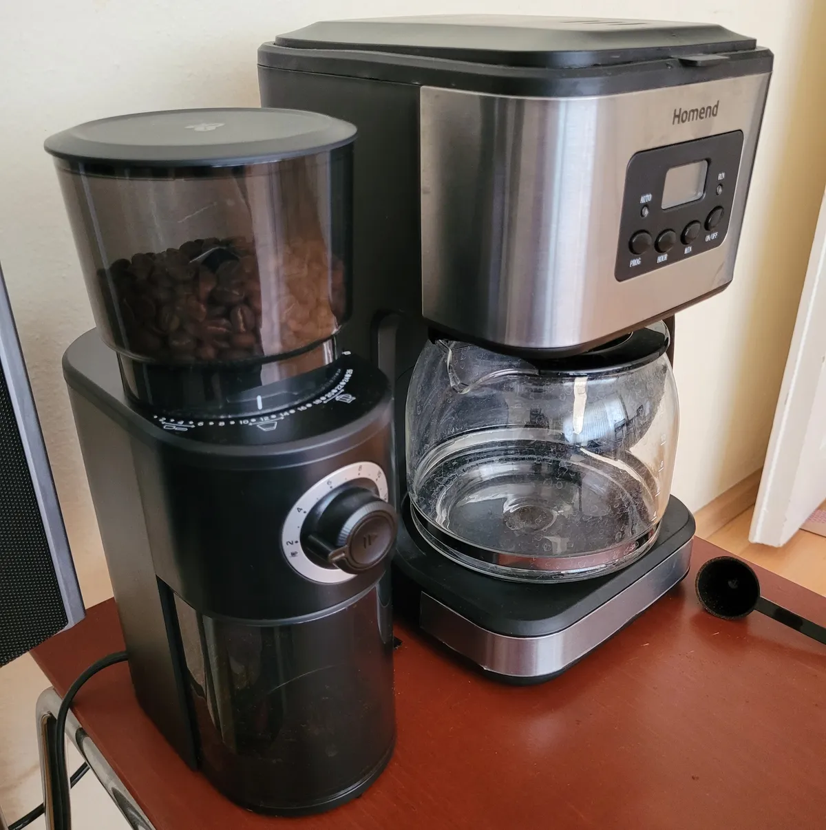 image of a coffee grinder along with a filter coffee machine sitting on a wooden coffee table (literally a coffee table)