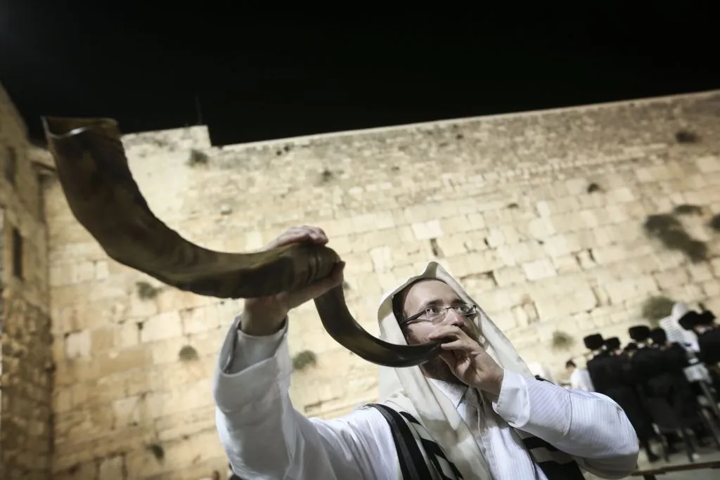上图：一个犹太人于赎罪日在哭墙吹响羊角号（Shofar）。
