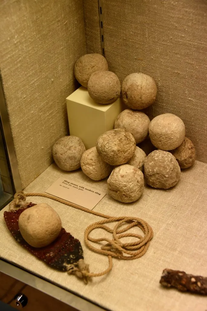 上图：从犹大拉吉城门口出土的亚述军攻城使用的机弦甩石（绳子是现代复制品）。现存于大英博物馆。