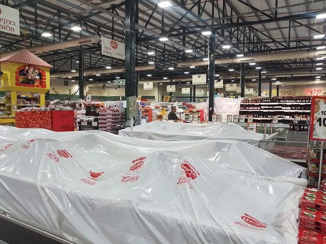 上图：从逾越节开始的7天无酵节期间，以色列的超市要有酵的食物（chametz）用白色塑料布遮盖起来。这些食物已经通过一位拉比签订合同，卖给了一位非犹太人，预付款1美元。但这些食物并没有离开超市，只是被挡住了，逾越节以后，超市还会以原价买回来。根据犹太宗教法典《哈拉卡 Halakha》，泡打粉（Baking Powder）和苏打粉（Baking Soda）不算酵，因为它们是通过化学反应、而不是生物发酵使食物膨松。