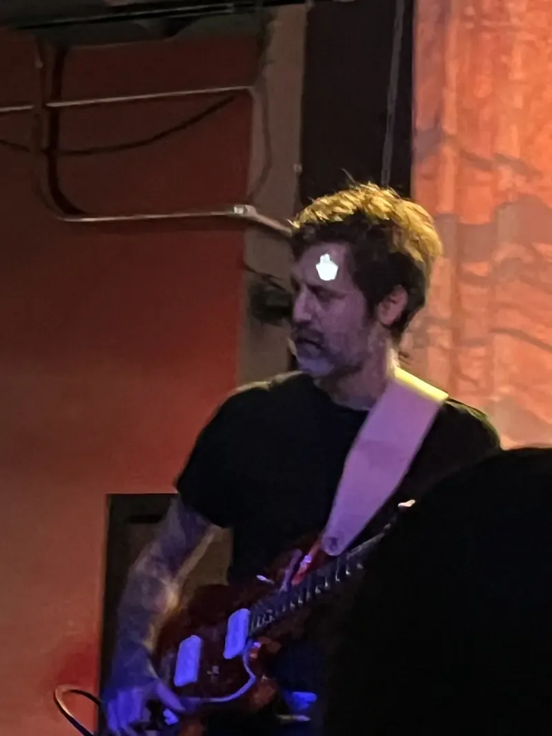 Guitarist on stage with a mouse pointer projected onto his face