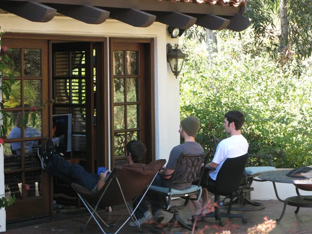 Three guys playing the N64 outside the poolhouse