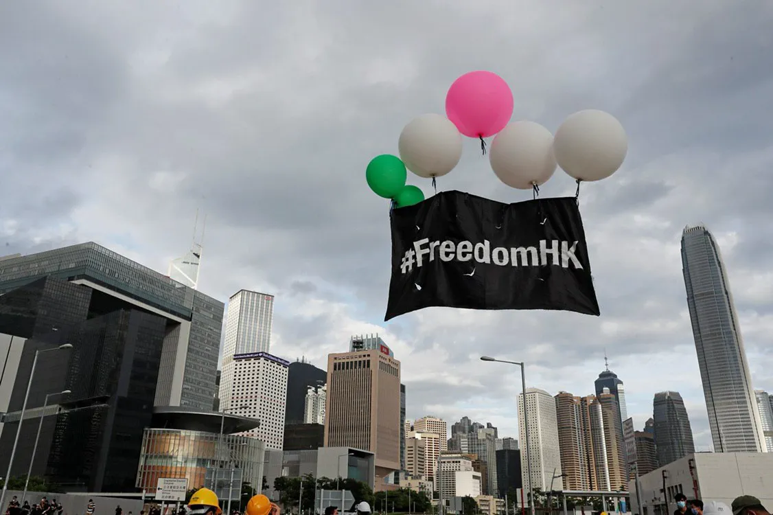Flag that says FreedomHK lifted into the sky by balloons