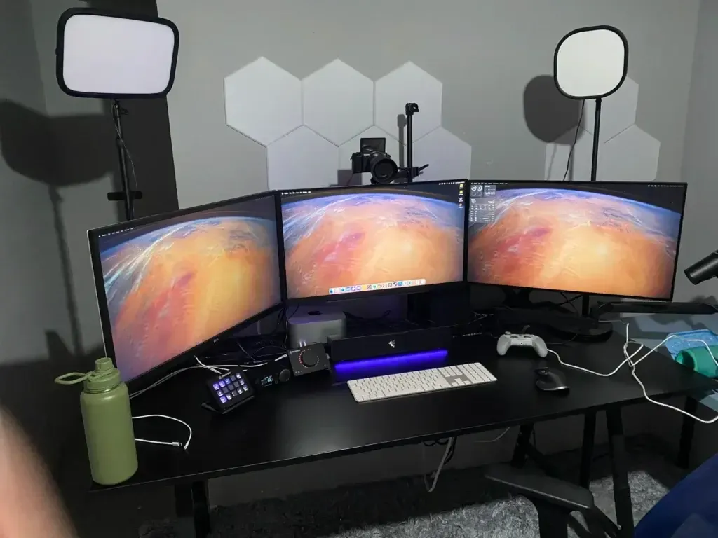 A picture of Ozject's home studio setup--featuring three monitors, a collection of streaming equipment, and a  Mac desktop.