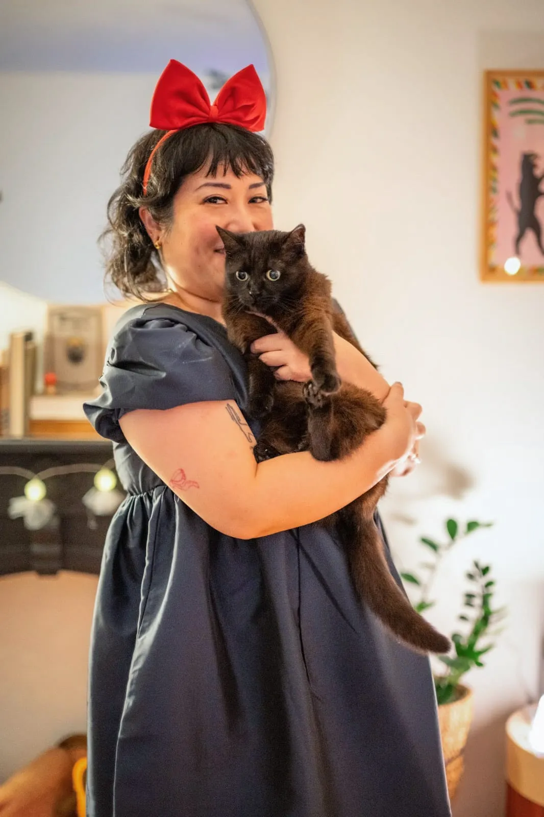 Peige holding Boba the black cat. Boba is looking downward with a concerned expression.