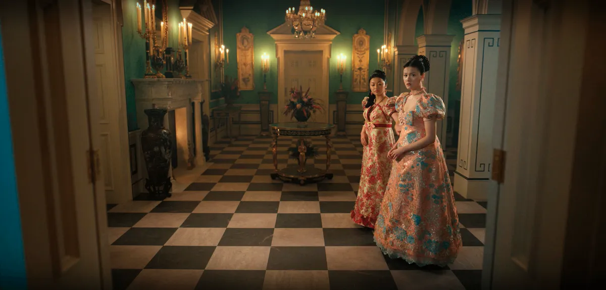 Rosamund and Posy stand inside the grand foyer of the Pendelwood House, with its signature green walls.