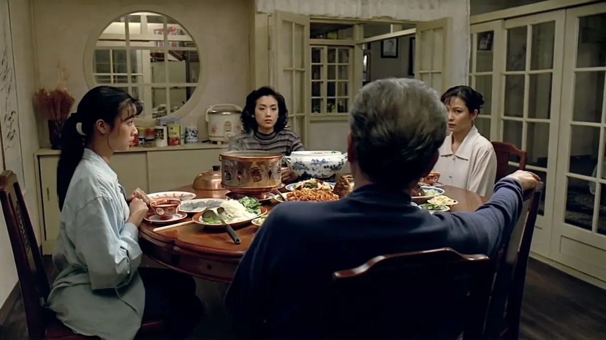 Three Taiwanese women sitting around a round table filled with food; an older man is sitting facing the women with his back towards the camera.