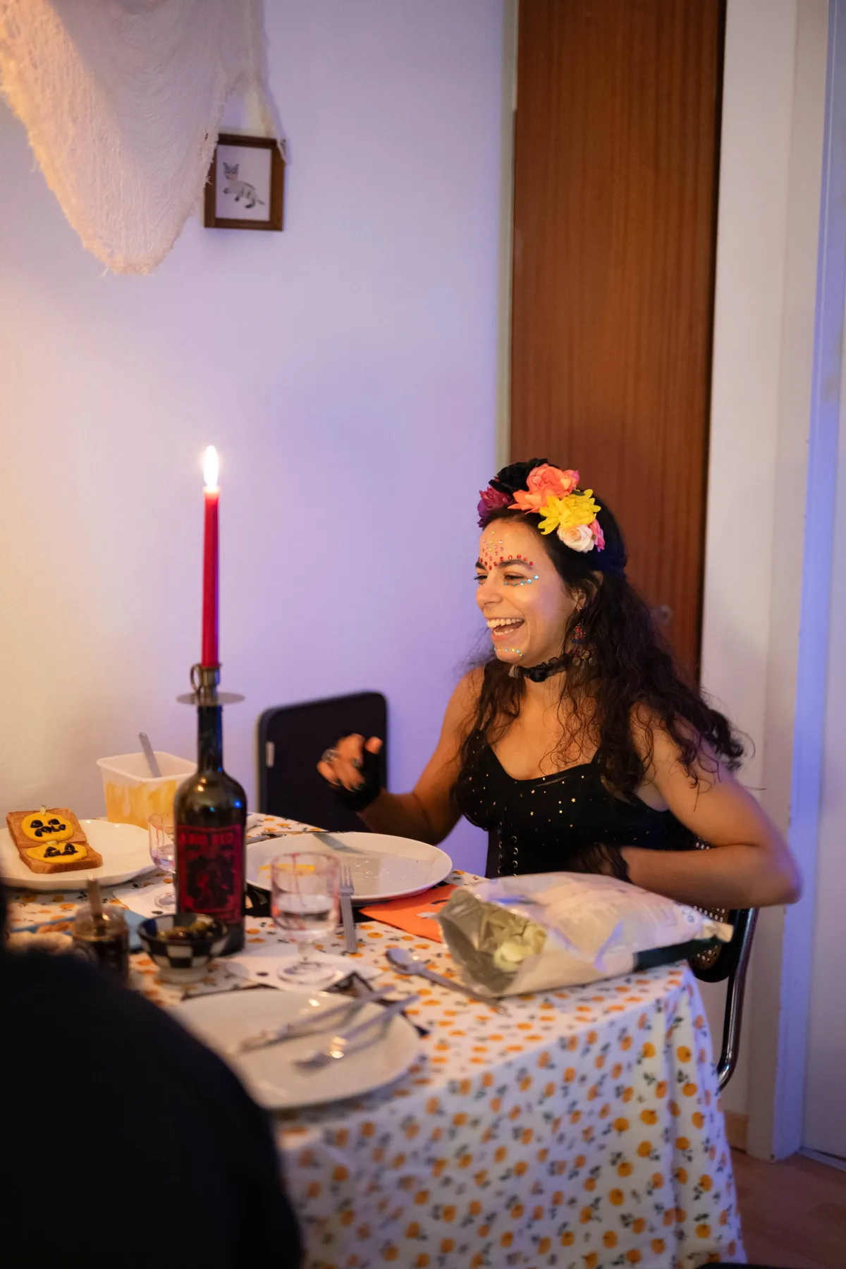 Eduarda sitting and smiling brightly. She is wearing a dress, flower crown, and has her face decorated with stick-on jewels.