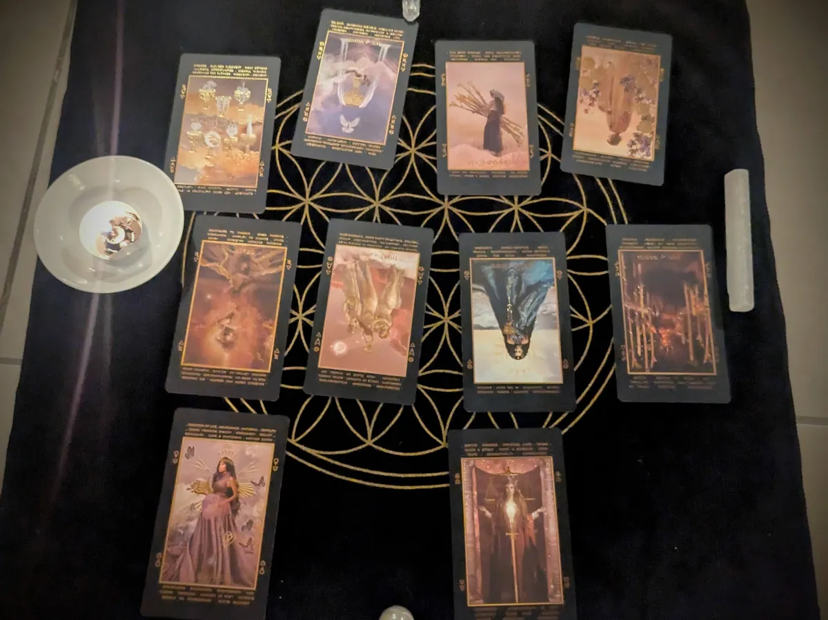 A spread of 10 tarot cards lie on top of a black cloth.