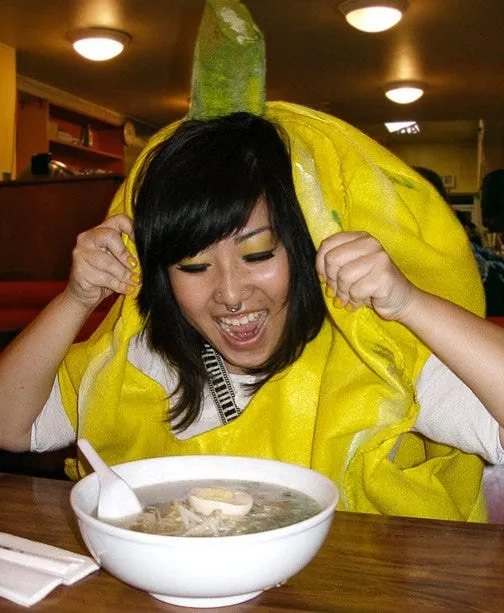 Peige dressed as a banana hovering over a bowl of ramen.