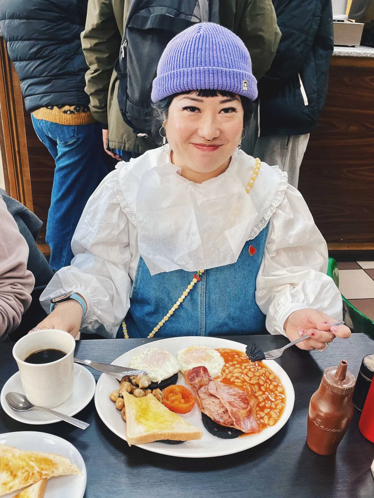 Peige smiling and posing with a full English breakfast plate.