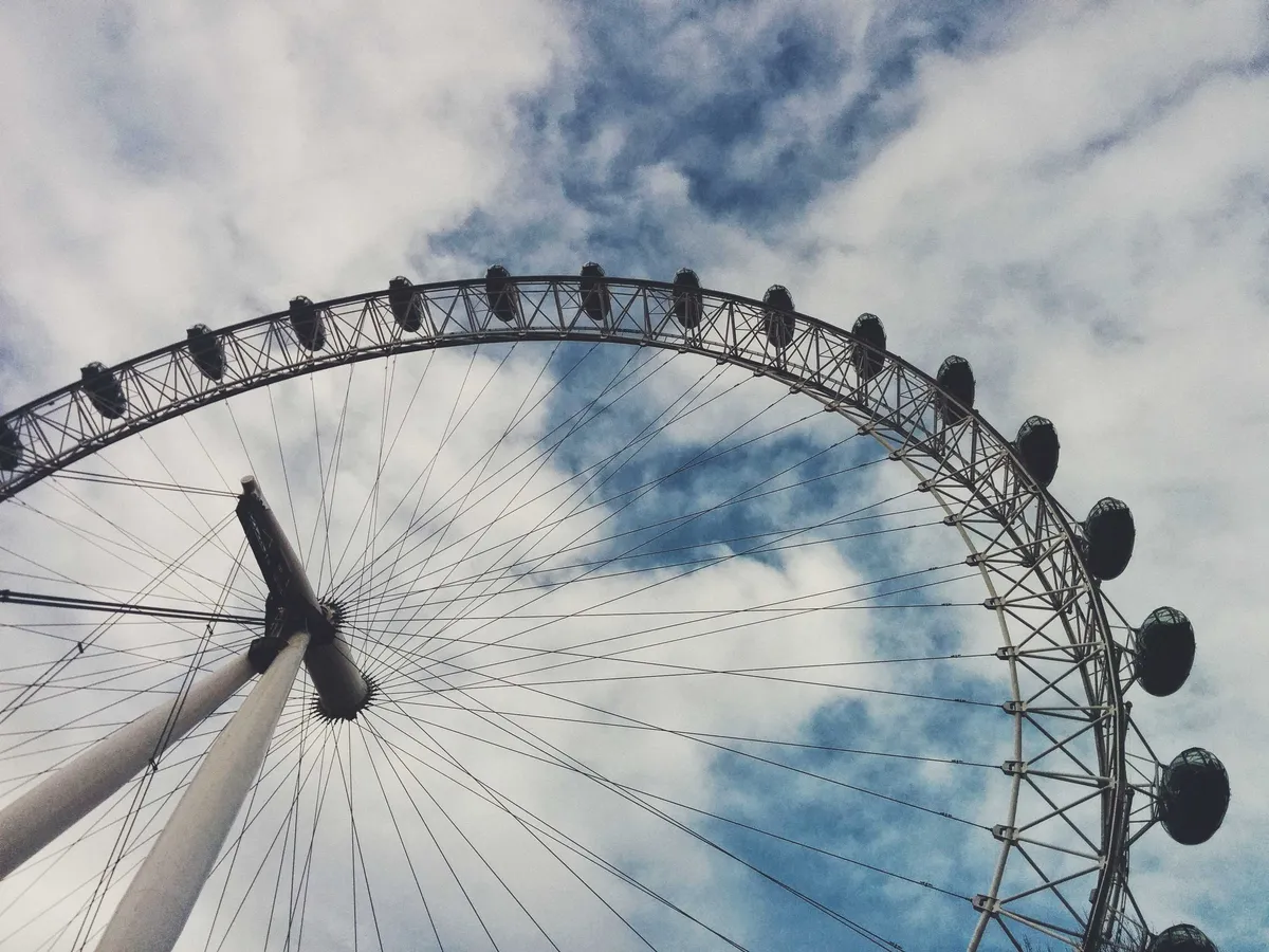 A giant ferris wheel against a cloudy blue sky.