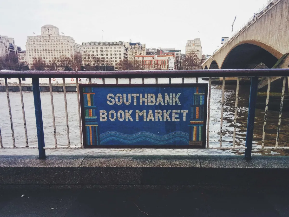 A tiled sign on the rails that says, "Southbank Book Market."