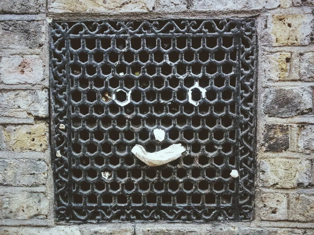 A metal grate in the wall with a happy face.