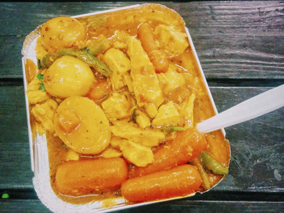 A small tray of yellow curry with two boiled eggs.