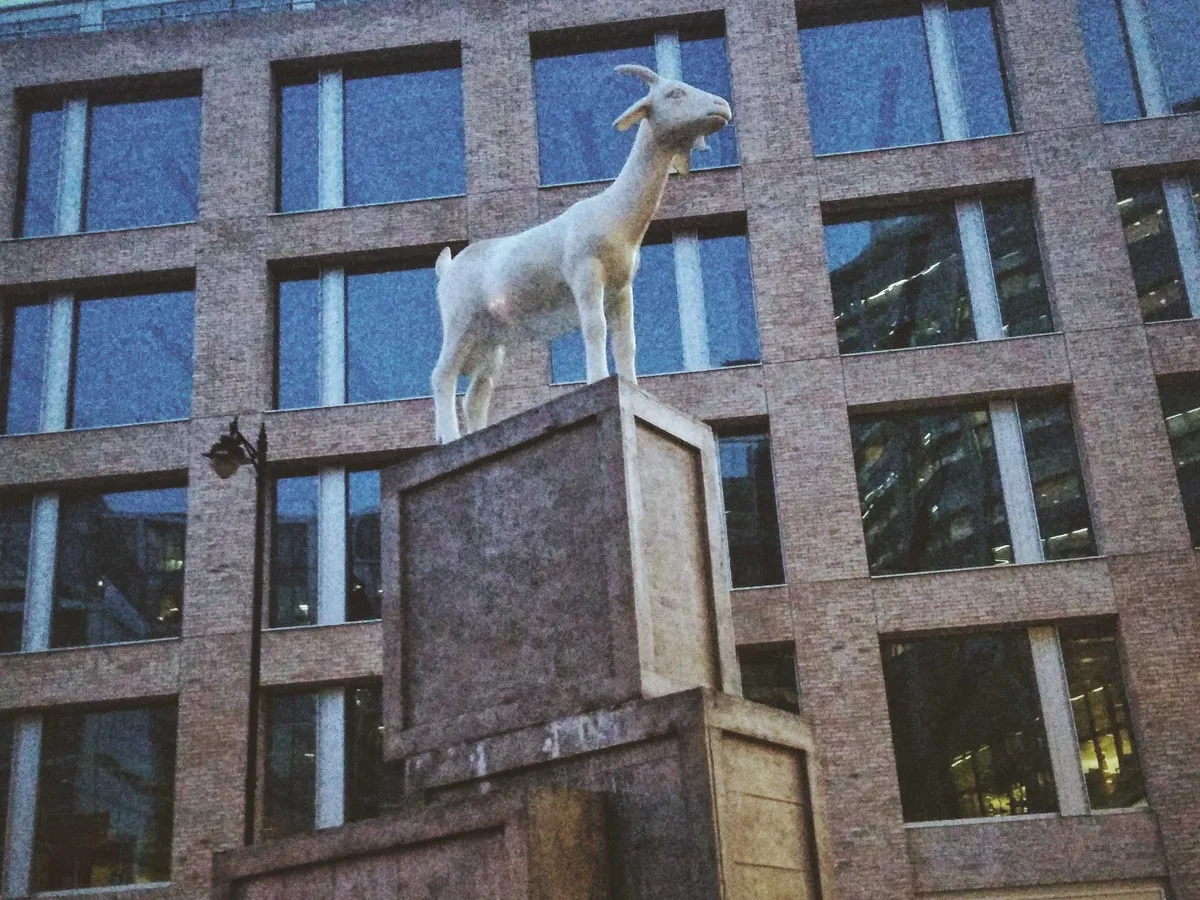 A statue of a small goat standing on several wooden crates.