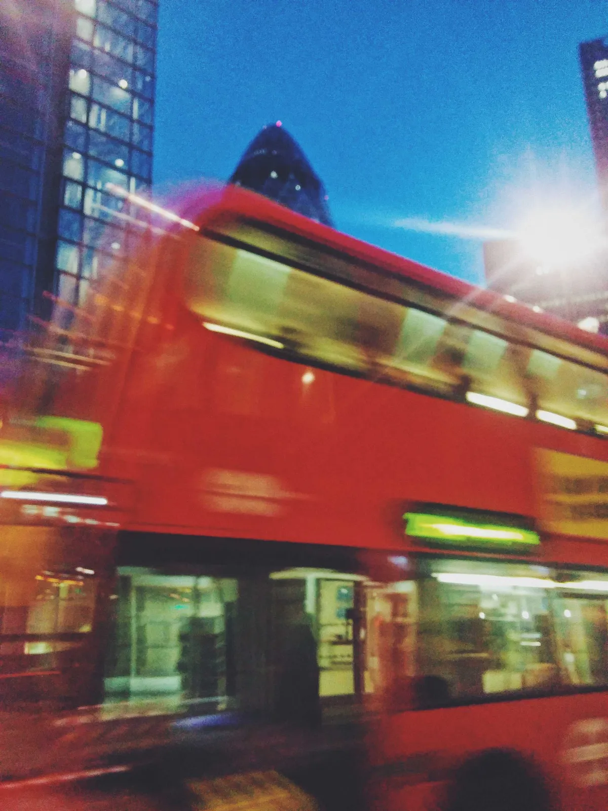 A blurry red double-decker bus driving across.