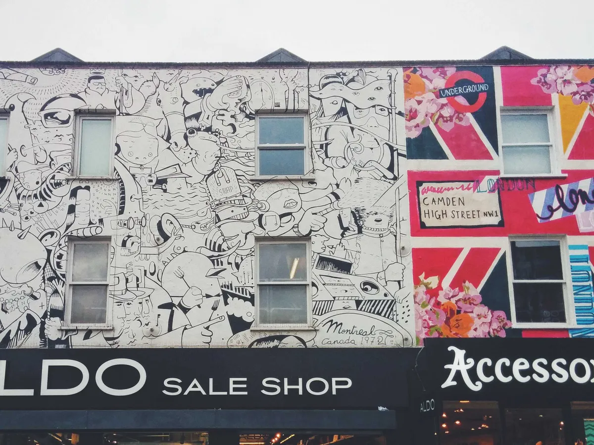 Street art covering the face of the buildings, above the shop signs.