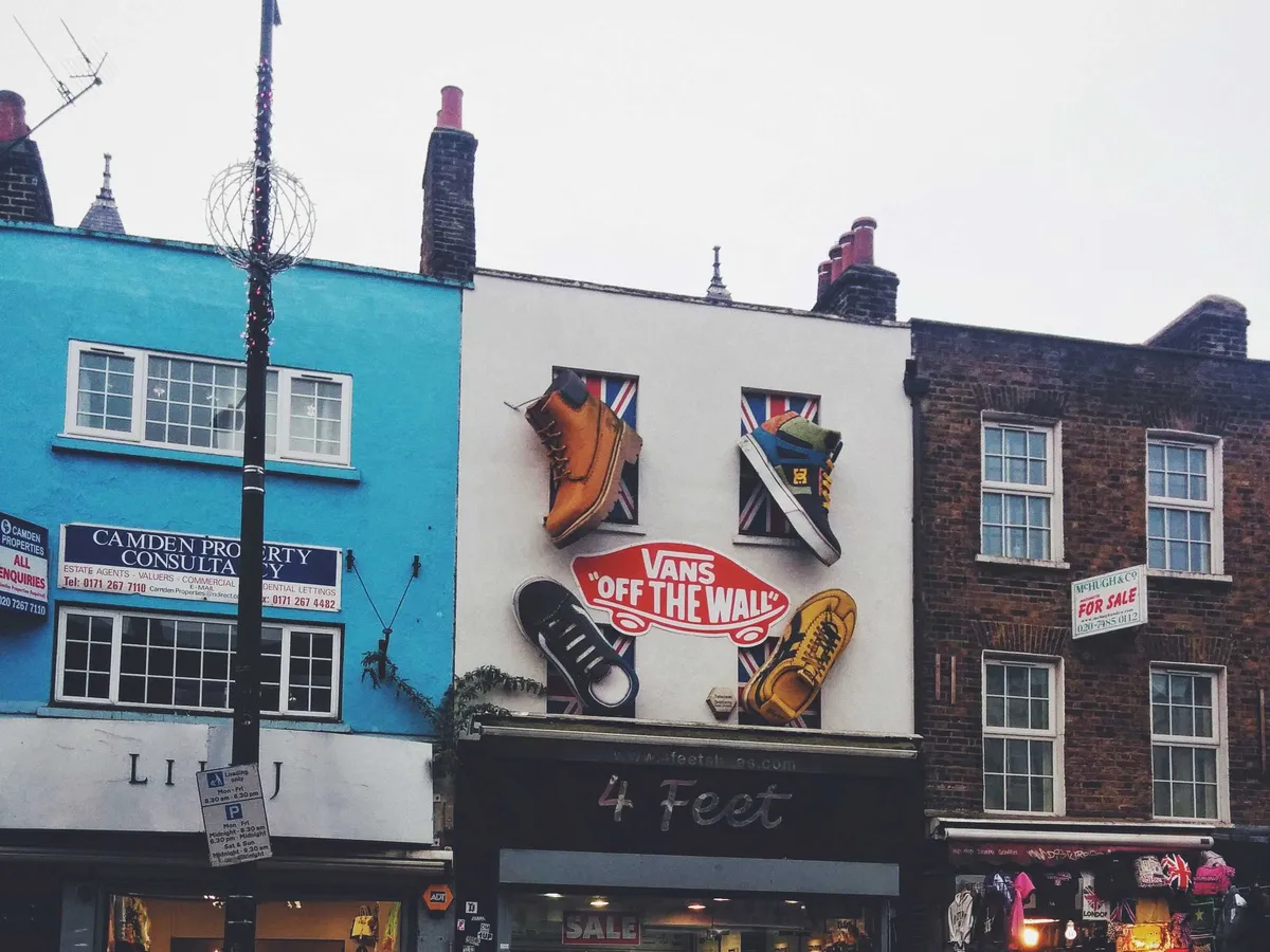 Giant replicas of branded shoes are installed on above a shoe shop, including a huge "Vans Off the Wall" sticker.