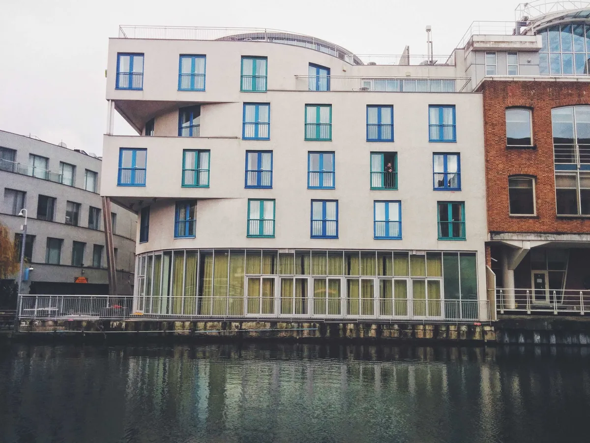A white modern building across the canal. The window frames alternate between various blue and teal colors.