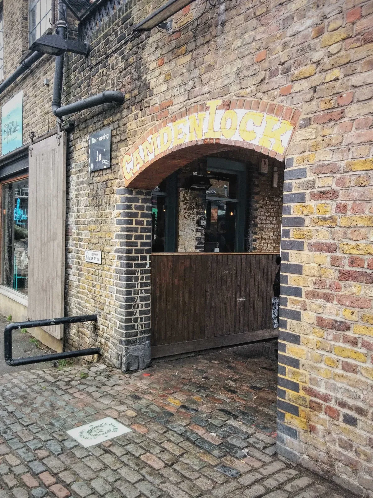 A brick archway with the words "Camden Lock" painted on it in yellow.