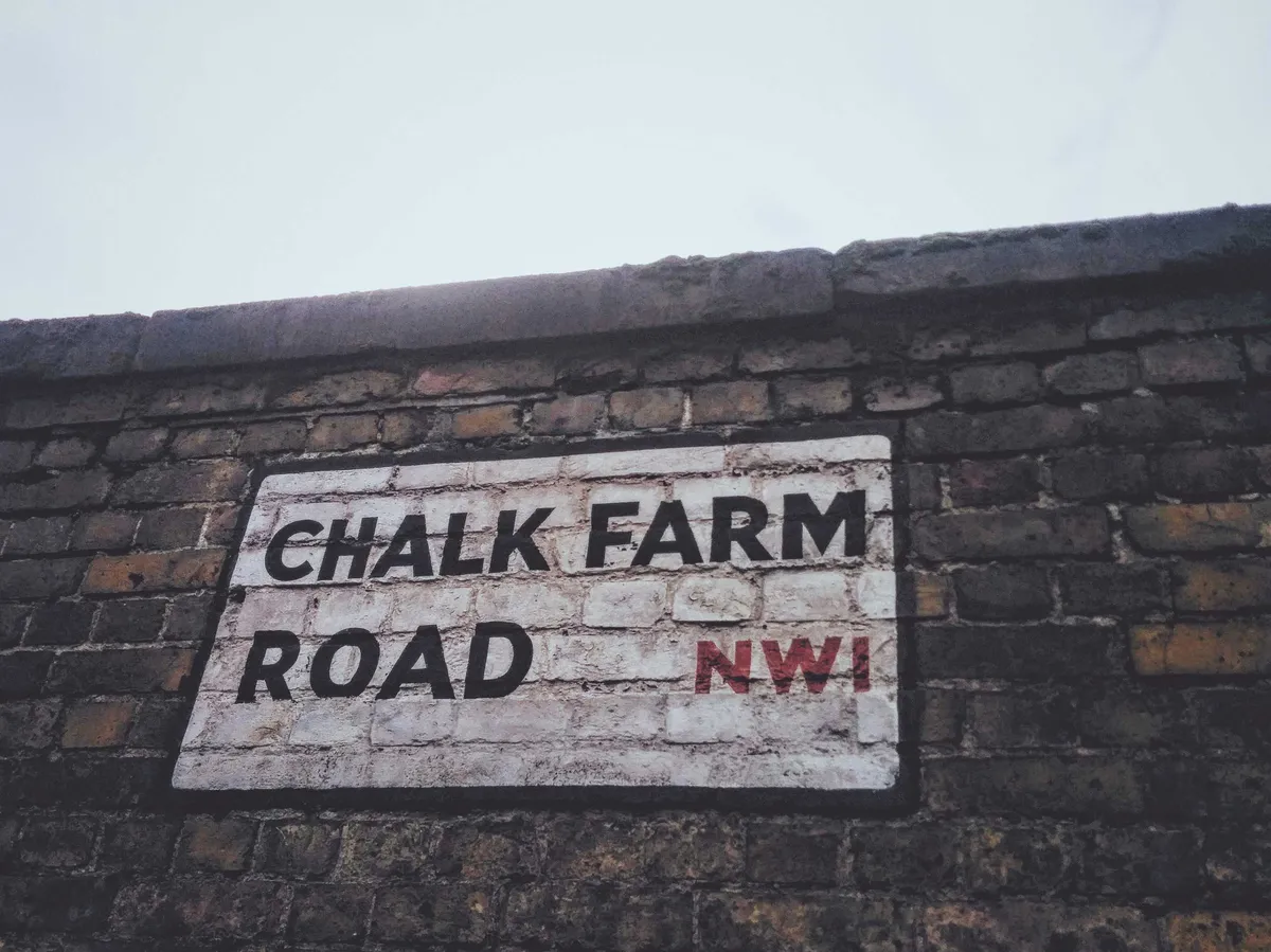 Close-up of "Chalk Farm Road NW1" painted on a brick wall.