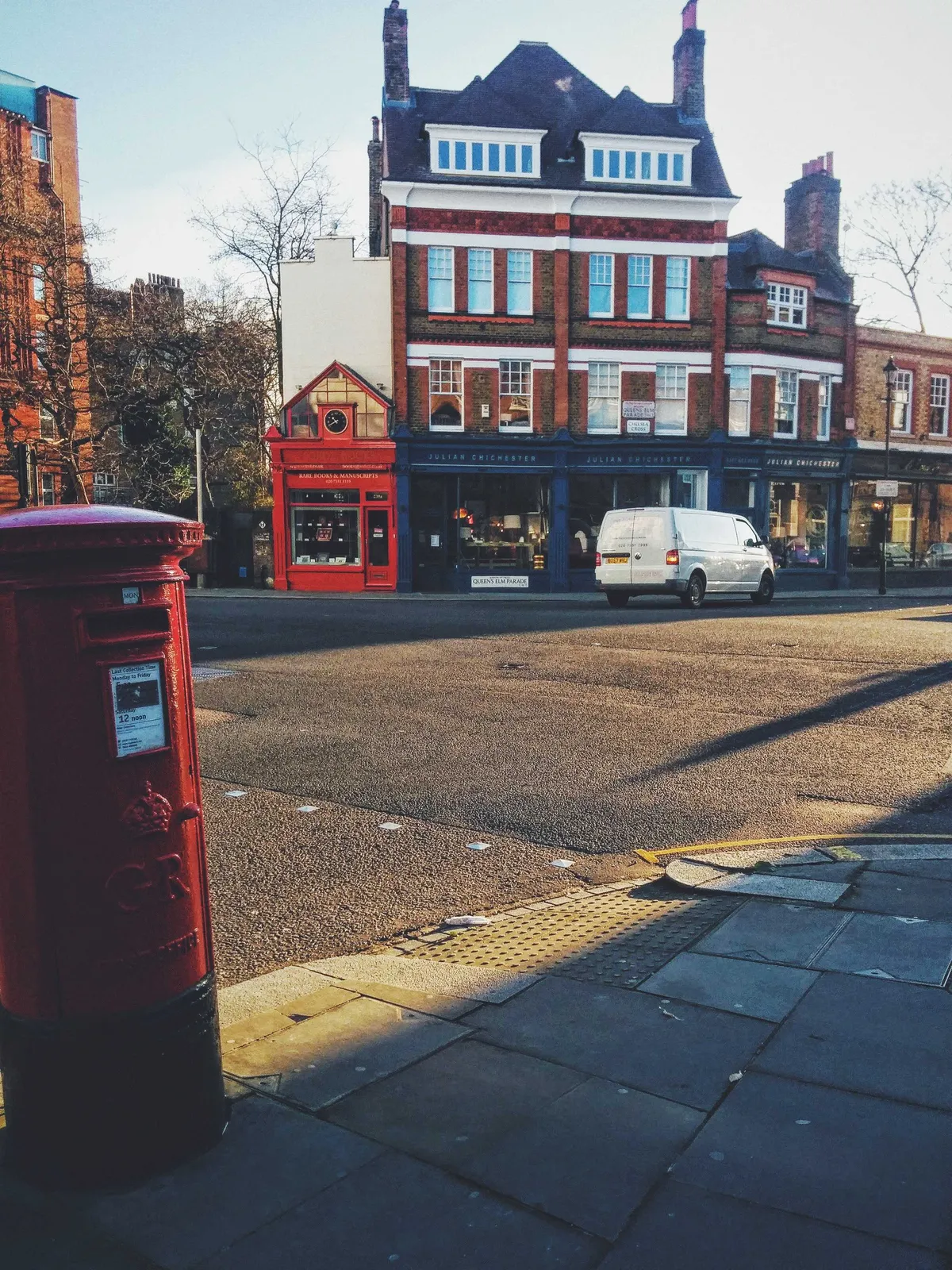 Red GR postbox on the corner of the sidewalk in the foreground. Georgian-era brick buildings in the background.