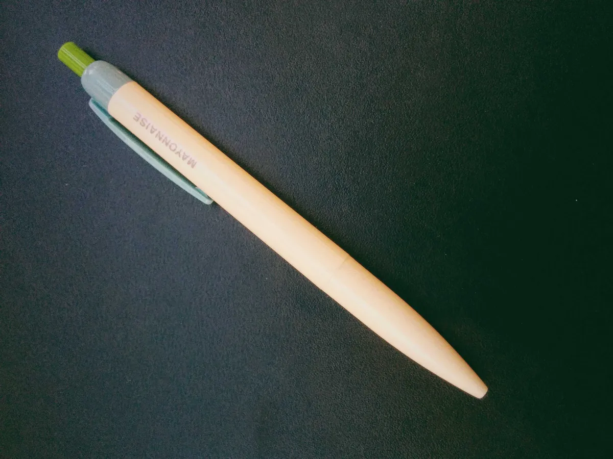 A cream colored, plastic ballpoint pen with grey text that says 