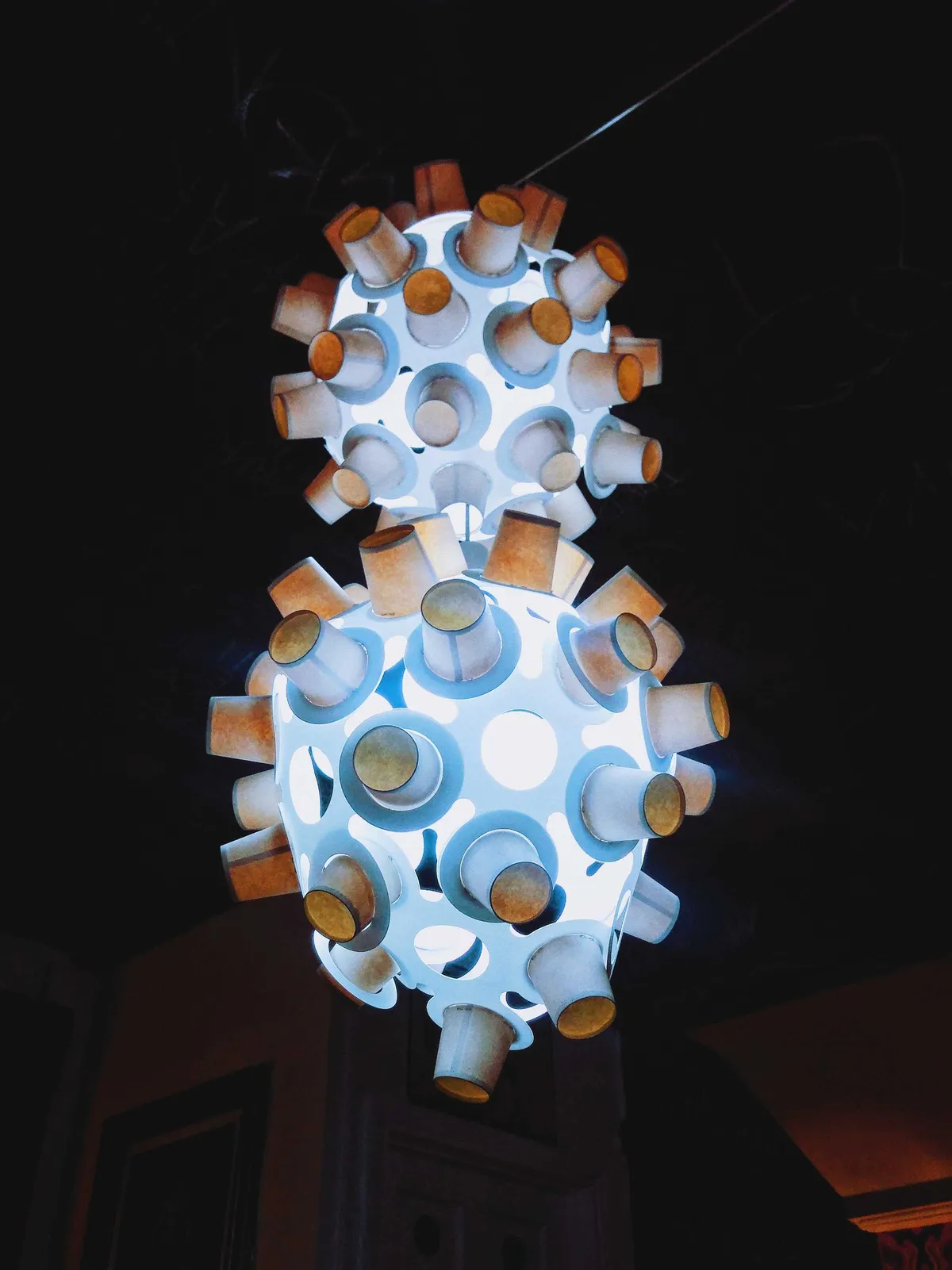 A lamp made out of paper cups and two round orbs.