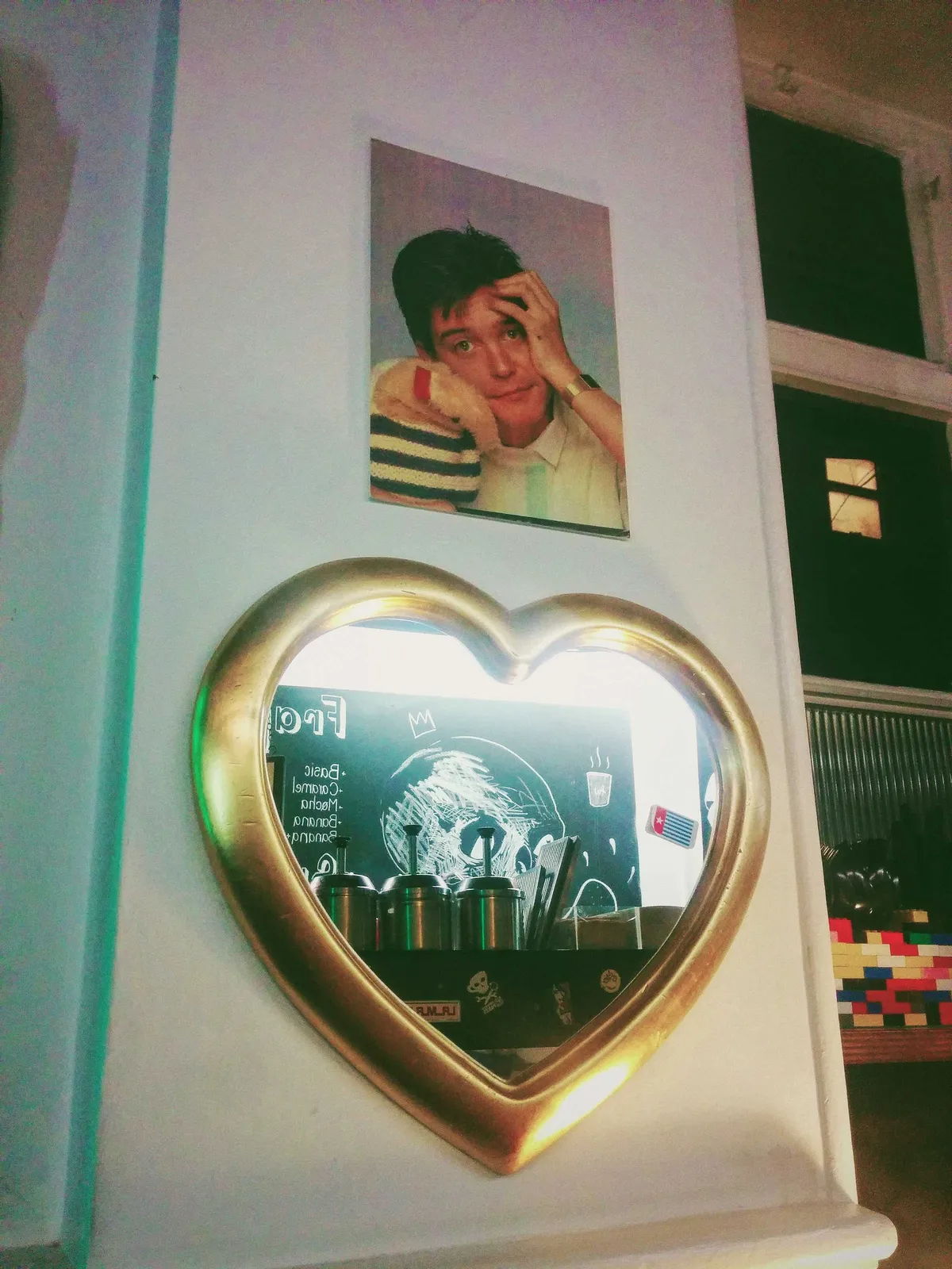 A photo of a man from the 1980s. Below is a gold-framed heart-shaped mirror.