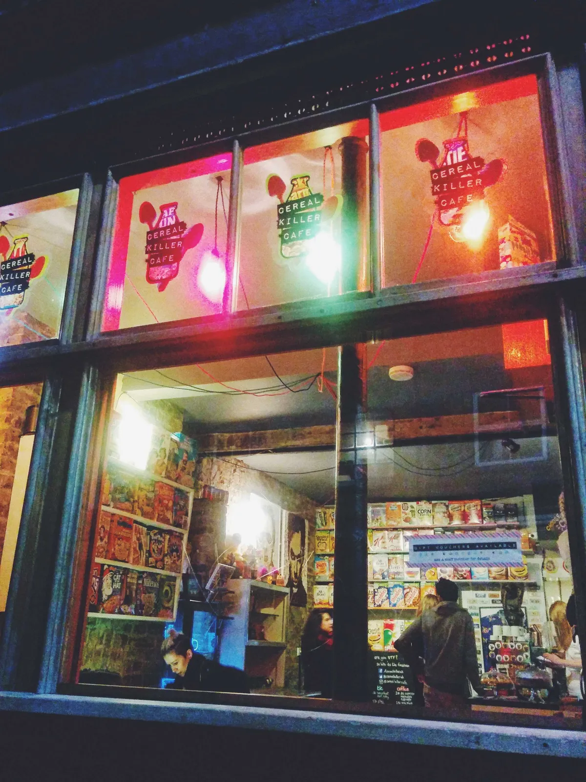 Peering into a café through the window. The shelves are lined with cereal boxes and patrons are inside. The logo 