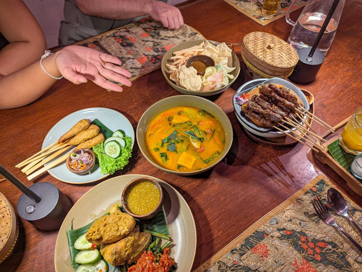 A colorful array of dishes including curries and meat satays.