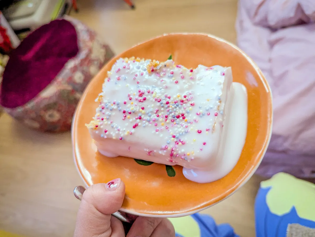 A glazed cake with colorful sprinkles on an orange plate.