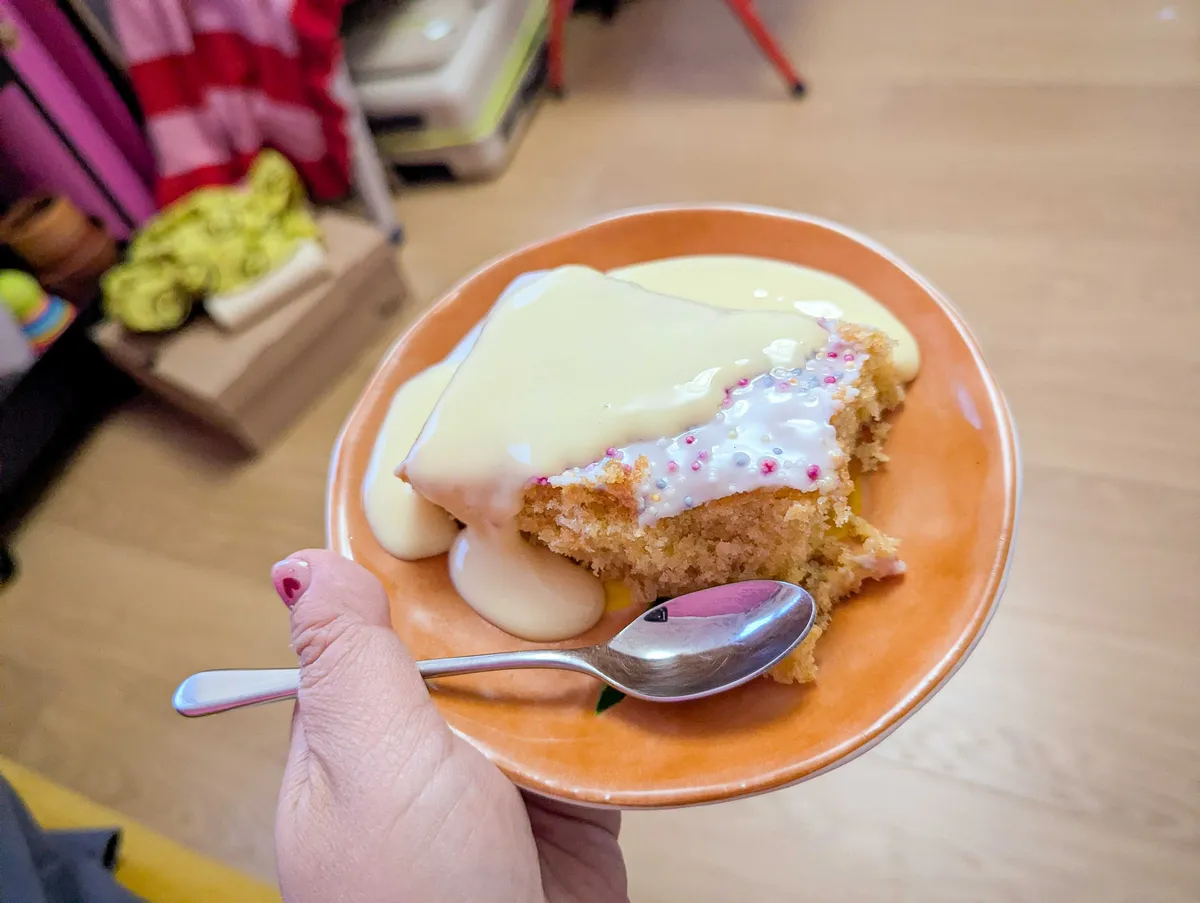 A bitten cake revealing yellow sponge. Cream-colored runny custard has been poured over the cake.