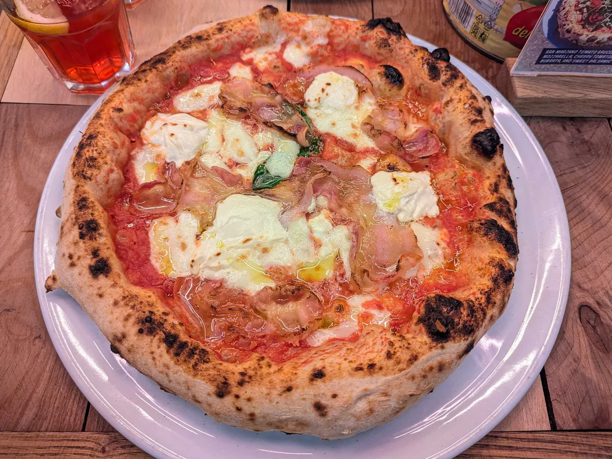 A fluffy crust circular pizza with lots of mascarpone and pancetta.