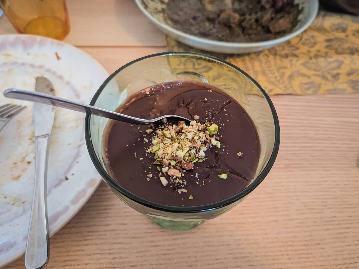 Chocolate pudding with chopped up pistachio on top, in a glass coupe.