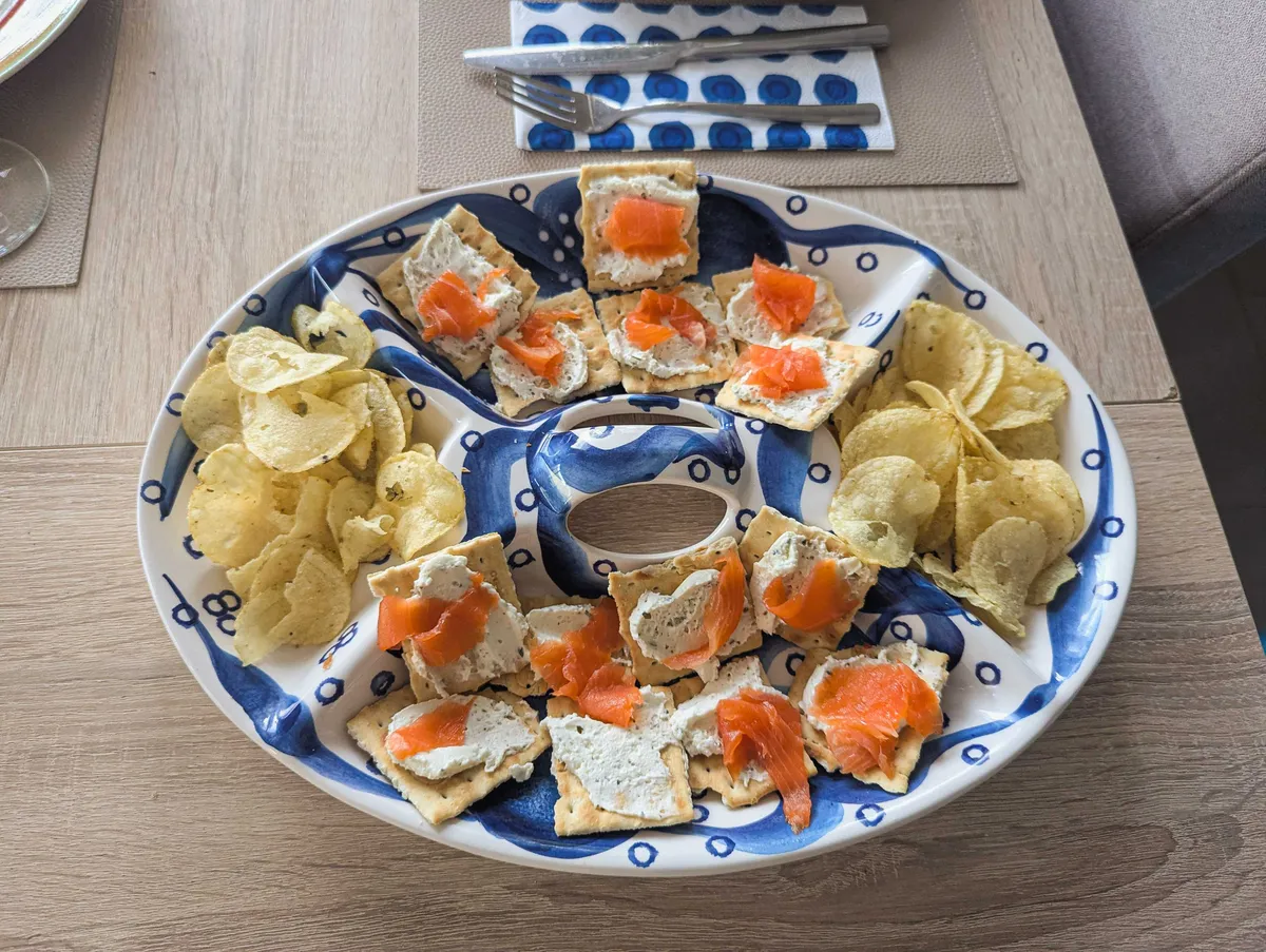 Chips and salmon crackers displayed on a blue and white oval porcelain plate.