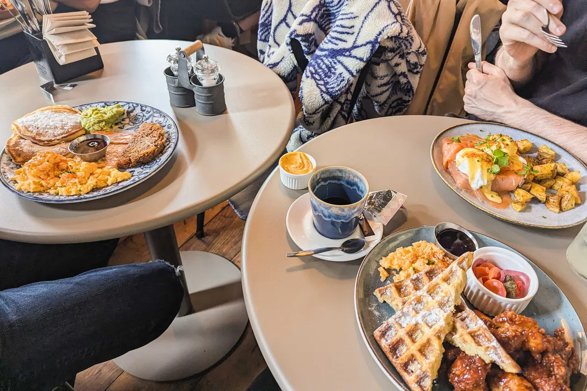 Three different breakfast plates: chicken and waffles, scrambled eggs with pancakes and hashbrowns, and salmon eggs benedict.